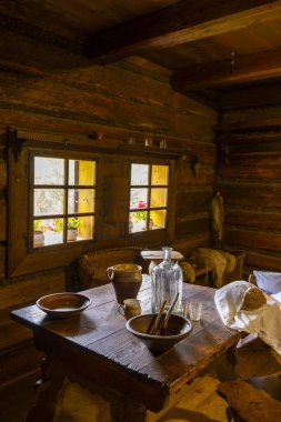 Geleneksel ahşap oda iç mimarisi pencere manzaralı bir masada sade ev eşyaları sunar.