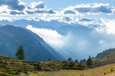 Orman dağları ve vadilerin üzerinden yükselen güneş ışınlarının yer aldığı dağlık bir arazi.