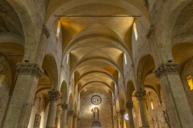 Kilisenin iç kısımlarında taş kolonlar, sivri kemerler ve içinde ışık olan bir tavan var.