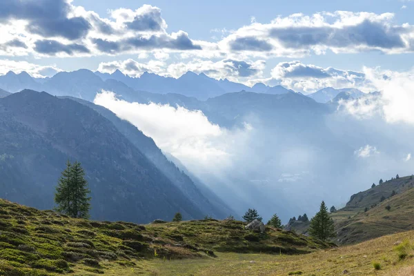 Orman dağları ve vadilerin üzerinden yükselen güneş ışınlarının yer aldığı dağlık bir arazi.