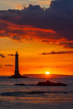 Goury deniz feneri dramatik bir turuncu ve kırmızı günbatımı gökyüzünün altında