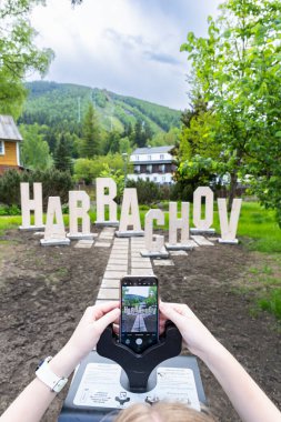 Liberecky Kraj, Çek Cumhuriyeti 'ndeki Harrachov tabelasını yakalamak için akıllı telefon kullanan kişi.