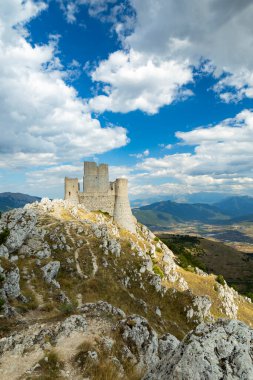 Antik Rocca Calascio kalesi engebeli bir tepede duruyor mavi gökyüzünün altında ve dağınık bulutların altında