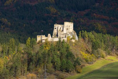Antik Likavka Kalesi Slovakya bayrağı dalgalanan bir tepenin üzerinde duruyor
