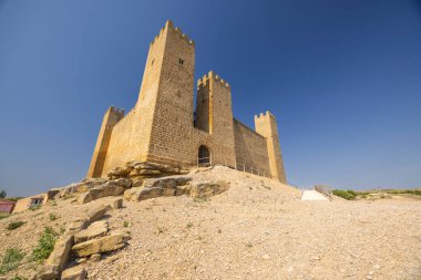Ortaçağ Sadaba şatosu mimarisi. Açık mavi gökyüzünün altında taş duvarları ve kuleleri var.