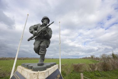 Normandiya kırsalındaki bir anma töreninde dikilen bir paraşütçünün bronz heykeli.