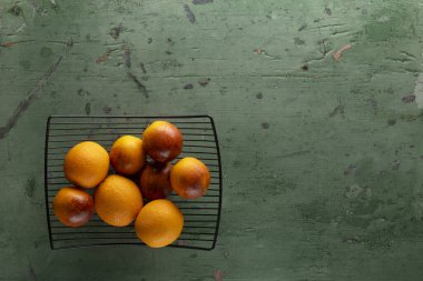 Taze narenciye, siyah metal bir rafta kırsal yeşil ahşap arka planda soğuyor.