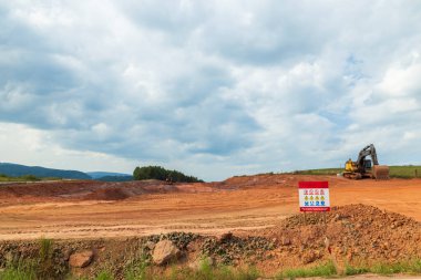 Gelişmekte olan bir inşaat alanında kırmızı toprağı şekillendiren yer değiştiren makineler.