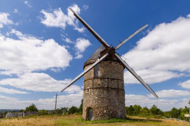 Beyaz bulutlu mavi gökyüzünün altında duran tarihi taş yel değirmeni