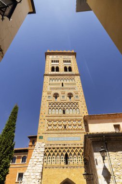 San Martin kilisesinin süslü Mudejar çan kulesi mavi gökyüzünün altında dar bir sokaktan yükseliyor.