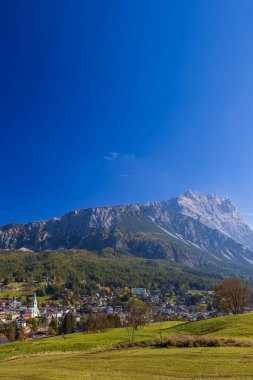 Cortina d 'Ampezzo kasabası Dolomites vadisinde berrak mavi gökyüzünün altında yuva yapmış.