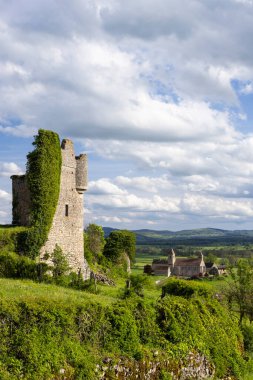 Fransız kırsalına bakan antik şato harabeleri. Arka planda tarihi bir köy kilisesi var.