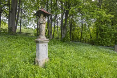 Meryem ve İsa 'nın heykeli canlı yeşil bir orman çayırında duruyor.