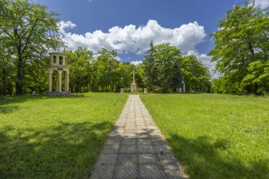 Yeşil çimlerden geçerek dini bir haça ve anıt köşke giden yol.