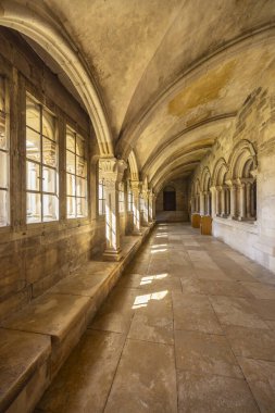 Tarihi bir manastırın taş kemerleri ve kubbeli tavanı. Pencereden güneş ışığı akıyor.