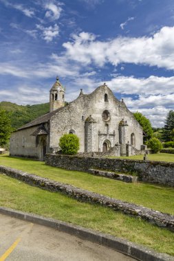 Yeşil çimenler ve mavi gökyüzüyle çevrili tarihi Romansı taş kilise binası