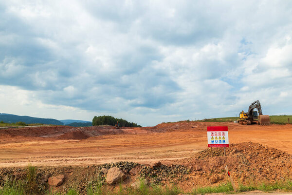 Землеройные машины, формирующие красную почву на развивающейся строительной площадке