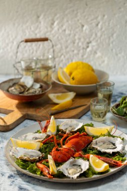Masada deniz ürünleri, ıstakoz, istiridye ve limon sunan beyaz şarap tabağı.
