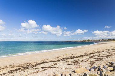 Fransa, Normandiya 'da, parlak bir yaz gökyüzü altında yumuşak dalgalarla kumlu sahil