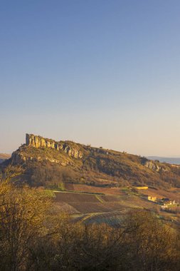 Roche de Solutre, Fransa 'da açık bir gökyüzünün altında hasat edilen üzüm bağlarının üzerinde duruyor.