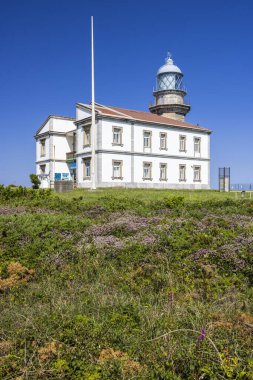Cabo Penas deniz feneri binası Gozon, İspanya 'da açık mavi gökyüzü altında seyrüsefer ve kıyı rehberliği sağlıyor.