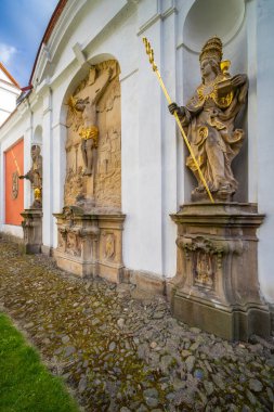 Taş barok heykeller manastırın dış duvarını kaldırım taşı yolu boyunca dekore ediyor.