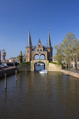 Kanal üzerinde uzanan tarihi Waterpoort binası ve içinden geçen küçük bir tekne.