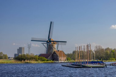 Tarihsel yel değirmeni ve Hollanda 'nın Warmond kentindeki sakin bir göle yanaşmış küçük tekneler.