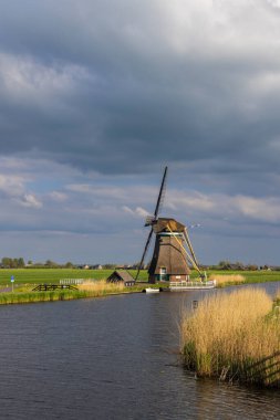 Groot Ammers, Güney Hollanda, Hollanda 'da bulutlu bir gökyüzü altında polder kanalı boyunca tarihi yel değirmeni