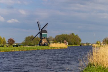 Geleneksel Hollanda rüzgar gülü Brandwijk 'te güneşli bir günde kanal kenarında su pompalıyor