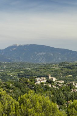 Vinsobres köyü güneşli bir günde arka planda Mont Ventoux ile bir tepede duruyor.