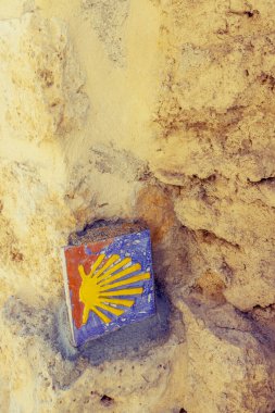Seramik deniz tarağı kabuğu sembolü. Eski bir taş duvarda Camino de Santiago sembolü.