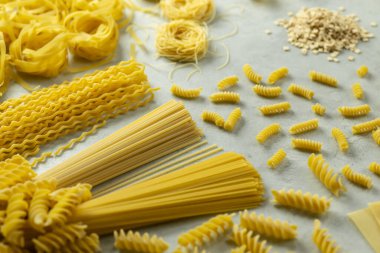 Çeşitli türde pişirilmemiş durum buğday makarnası hafif arkaplanda canlı bir görüntü oluşturur