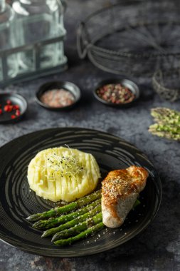 Kızarmış tavuk, yeşil kuşkonmaz ve lahanayla süslenmiş patates püresi.