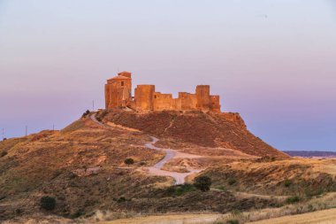 Antik Castillo de Montearagon tarihi yeri, alacakaranlıktaki tepede bir kale.