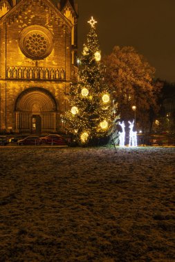 Prag 'daki bir kilisenin dışında gece vakti aydınlatılmış Noel ağacı ve ren geyiği süslemeleri.
