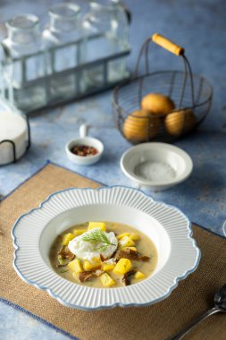 Kremalı mantar ve haşlanmış yumurta ve mavi masada taze dereotlu patates çorbası.