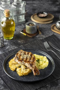 Kızarmış domuz pirzolası yemeye hazır patates püresi ve kavrulmuş karnabahar ile servis edilen akşam yemeği.