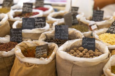 Fransa 'nın Nyons kentindeki tekstil torbalarında çeşitli baharat ve fındık çeşitleri sunan pazar tezgahı.