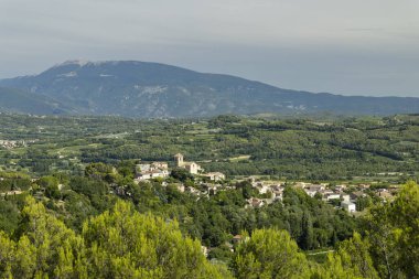 Vinsobres köyü arka planda Mont Ventoux ile yeşil tepelerin ve üzüm bağlarının arasında oturuyor.