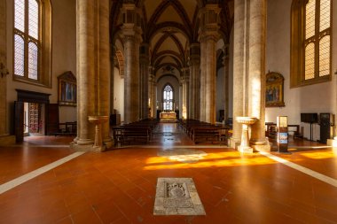 Duomo di Pienza iç mimarisinde taş sütunlar, yüksek tavanlar ve teraslarda güneş ışığı var.