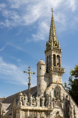 Fransa 'nın Finistere şehrinde mavi gökyüzü altında taş kilise ve süvariler.