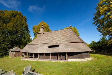 Aziz Mikail 'in tarihi ahşap kilisesi mavi gökyüzü ile yeşil çimlerin üzerinde duruyor.