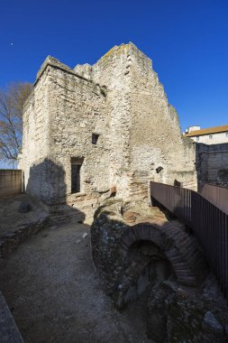 Arles 'teki açık mavi gökyüzünün altında antik Roma duvarları kalıntıları ve taş yapılar.