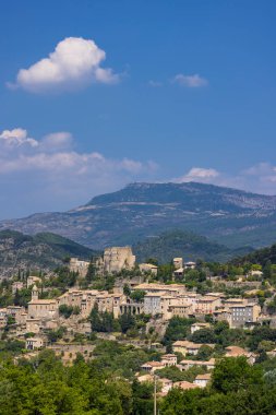 Montbrun les Bains köy binaları bir yamaçta yuva yapmış ve arka planda dağlar oluşmuş.