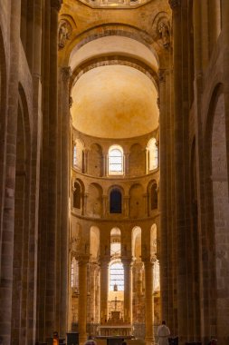 Manastır kilisesinin iç kısmı sunağın etrafında antik Romanca mimari, kemer ve sıcak ışığı gösteriyor.