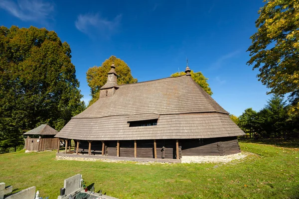Aziz Mikail 'in tarihi ahşap kilisesi mavi gökyüzü ile yeşil çimlerin üzerinde duruyor.