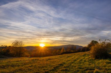 Slovakya 'da kırsal bir sonbahar tarlasında güneş turuncu ve kırmızı batıyor