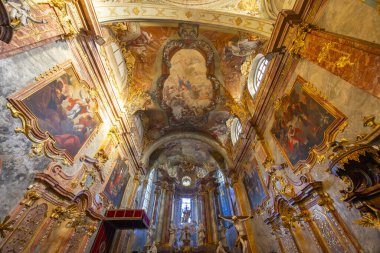 Barok kilisesinin içinde freskler, yaldızlı sıva ve dini heykeller var.