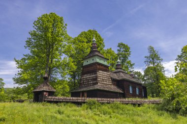 Antik ahşap kilise Bartne 'daki yeşil ilkbahar ağaçları ve otların arasında duruyor.